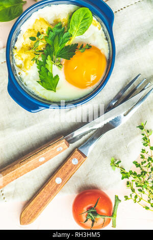 Oeufs cuits en bleu moules de cuisson en céramique. Cocotte de légumes et portionné oeufs dans un style italien ou français. Oeufs cocotte kokot petit-déjeuner. Haut Banque D'Images