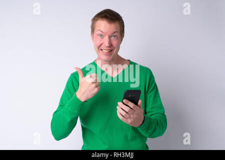 Happy young man using phone et giving Thumbs up Banque D'Images