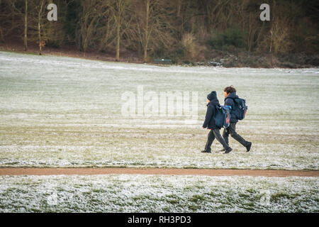 Manchester, UK - 30 janvier 2019 - schoolschildren à pied à l'école à travers un champ couvert de neige, par un froid matin d'hiver au Royaume-Uni ; Banque D'Images