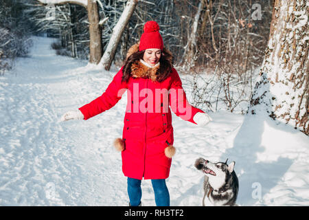 Jeune femme jouant avec son chien husky dans winter park Banque D'Images