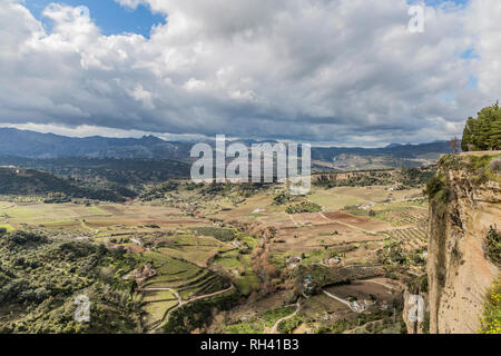 Vue sur une vallée avec des zones de pâturage et de l'horticulture entouré de montagnes vu de la ville Ronda sur une journée avec l'abondance des nuages blancs en Espagne Banque D'Images