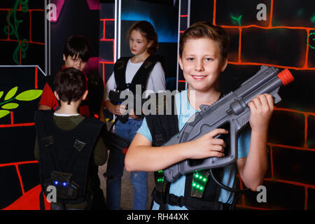 Portrait of smiling preteen boy positif avec pistolet laser posant en labyrinthe laser tag Banque D'Images