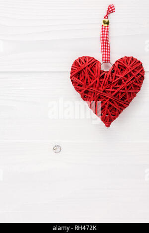 Coeur en osier blanc accrochés sur une planche de bois. Valentines Day card concept avec copie espace pour le texte. Banque D'Images