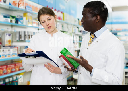 Les jeunes pharmaciens expérimentés la prise d'inventaire des médicaments en pharmacie Banque D'Images