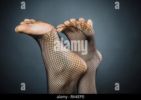 Pieds de womans piquer à travers bas résille Banque D'Images