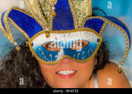 Belle image du visage d'une jeune femme en cheveux noirs frisés portant un masque de Venise avec une combinaison de bleu, blanc et or Banque D'Images