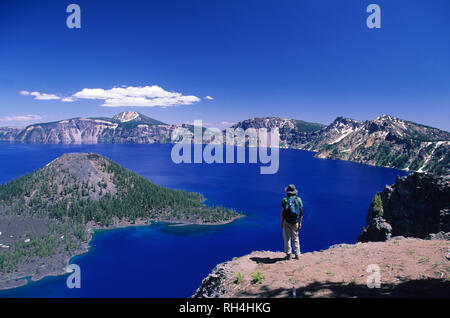 Vue arrière d'un homme debout sur une falaise surplombant le lac du cratère. Banque D'Images