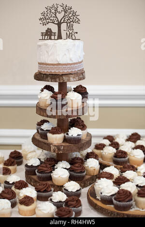 Gâteau de mariage et gâteaux de cupcakes lors d'une réception à thème rustique Banque D'Images