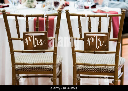 M. & Mme panneaux en bois rustique sur les chaises de mariée et de marié lors d'une réception de mariage dans une salle de restauration Banque D'Images