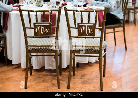 M. & Mme panneaux en bois rustique sur les chaises de mariée et de marié lors d'une réception de mariage dans une salle de restauration Banque D'Images