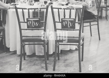 M. & Mme panneaux en bois rustique sur les chaises de mariée et de marié lors d'une réception de mariage dans une salle de restauration image noir et blanc Banque D'Images