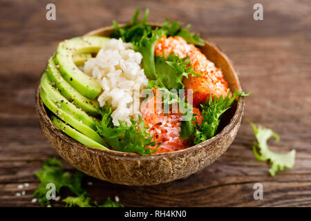 Hawaiian poke bol de noix de coco avec du saumon grillé du poisson, du riz et d'avocat. L'alimentation saine Banque D'Images