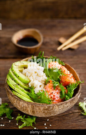 Hawaiian poke bol de noix de coco avec du saumon grillé du poisson, du riz et d'avocat. L'alimentation saine Banque D'Images