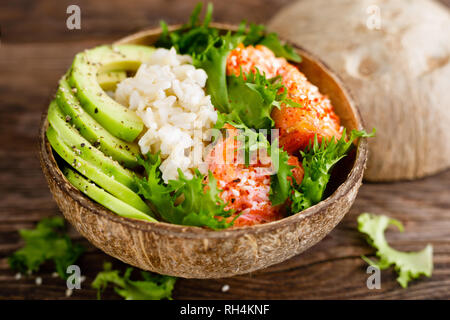 Hawaiian poke bol de noix de coco avec du saumon grillé du poisson, du riz et d'avocat. L'alimentation saine Banque D'Images