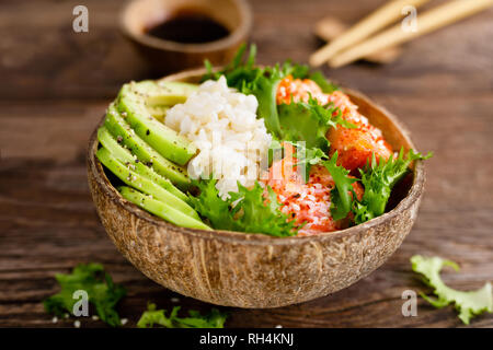 Hawaiian poke bol de noix de coco avec du saumon grillé du poisson, du riz et d'avocat. L'alimentation saine Banque D'Images