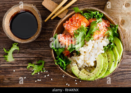 Hawaiian poke bol de noix de coco avec du saumon grillé du poisson, du riz et d'avocat. Alimentation saine. Vue d'en haut Banque D'Images