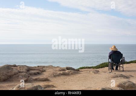 Une personne assise sur une falaise, l'observation des baleines, à Bodega Head, Californie, USA. Banque D'Images