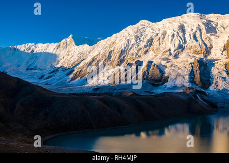 Vue panoramique sur le lac Tilicho au sommet couvert de neige de Kangsar Kang au lever du soleil Banque D'Images