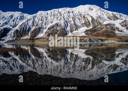 Vue panoramique sur le lac Tilicho, le sommet couvert de neige et les pentes du Tilicho Peak, au lever du soleil Banque D'Images