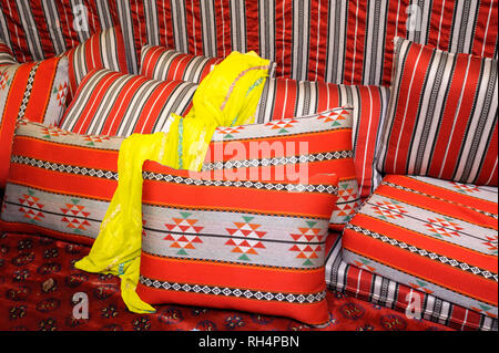 Robe jaune arabes traditionnelles portant sur un coussin, quelques coussins placés autour de Banque D'Images