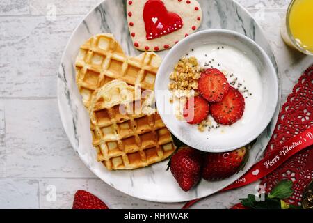 Valentines Day breakfast gaufres en forme de coeur bol de granola yogourt fraises fraîches, overhead view Banque D'Images