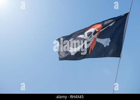 Noir et blanc du drapeau pirate vole sur ciel bleu. Banque D'Images