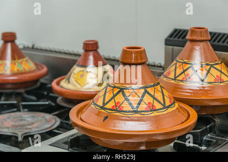 L'argile marocaine tajines avec différents décors sur une cuisinière dans une cuisine, la préparation du ragoût de tajin sur un feu lent mul Banque D'Images