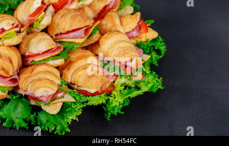 Un croissant avec du fromage et de la saucisse aux herbes. sur fond sombre Banque D'Images