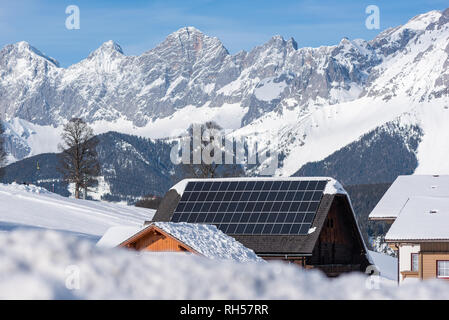 Panneau solaire, panneaux photovoltaïques PV sur un toit de maison. Électricité à partir de l'énergie solaire. Maison avec des montagnes enneigées à l'arrière-plan. L'Autriche Banque D'Images
