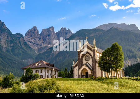 L'église Saint-Sébastien à Falcade sur une journée ensoleillée avec les sommets de l'arrière-plan dans le groupe Pala Banque D'Images