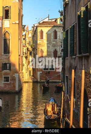 Une télécabine parqué avec deux gondoles derrière elle sur un canal dans le quartier Cannaregio de Venise à l'heure d'or Banque D'Images