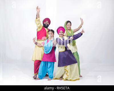 PORTRAIT D'UNE FAMILLE DE QUATRE SARDAR SIKH LA DANSE DANSE EN COSTUME TRAIDITIONAL BANGRA Banque D'Images