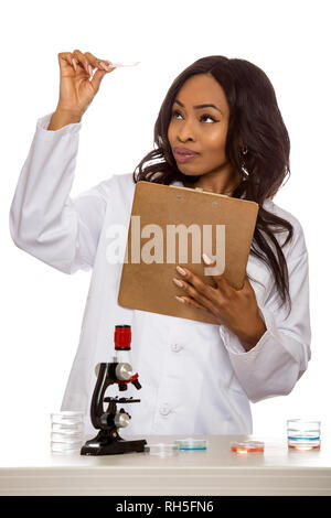 Black female scientist portant un manteau de laboratoire avec microscope et pétri de faire de la recherche sur la biologie des micro. Elle travaille dans l'éducation médicale ou ind Banque D'Images