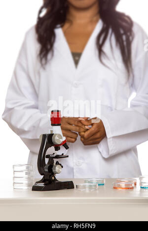 Black female scientist portant un manteau de laboratoire avec microscope et pétri de faire de la recherche sur la biologie des micro. Elle travaille dans l'éducation médicale ou ind Banque D'Images