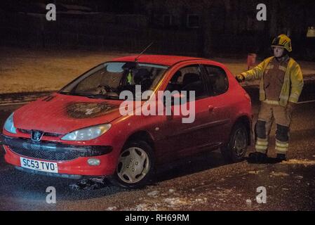 Un membre du Service des incendies est vu debout à côté de la voiture avec le feu visible sur le capot. Une voiture a pris feu ce soir sur la B9096 en Tullibody. La police et d'incendie et de sauvetage étaient sur scène. Il n'y a pas de blessés. Fire & Rescue mis le feu et l'éteindre. Banque D'Images