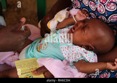 Mopti, Mali. Mar 22, 2018. Une jeune mère est tenant son bébé qui pleure sur ses genoux, tandis qu'un employé du centre de santé est l'administration d'un vaccin pour l'enfant. La mère tient sa carte de vaccination du bébé dans la main gauche. Credit : Jürgen Bätz/dpa/Alamy Live News Banque D'Images