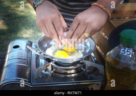Libre d'une paire de mains fissurer un oeuf dans une casserole Banque D'Images