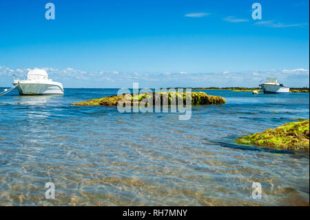 Deux bateaux flottant près de la plage sur l'eau avec des pierres en été sur l'île de Noirmoutier Banque D'Images