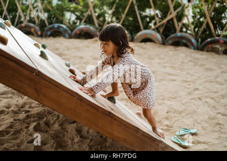 Portrait d'une vue de côté une petite fille commencent à essayer monter sur la planche de bois monter Banque D'Images