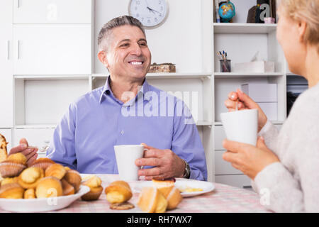 Couple marié de prendre le petit-déjeuner et prendre un café avec des gâteaux à la table dans la cuisine Banque D'Images