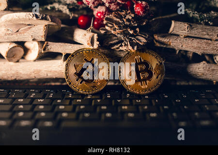 Bitcoin lumineux debout sur le clavier avec fond de noël. Or deux chrstimas bitcoins au moment sur fond de bois.