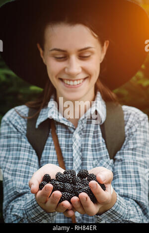 Fruits biologiques. Heureux et smiling girl in hat continue de mûres fraîches. Concept de la saine alimentation Banque D'Images