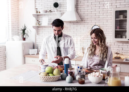 Jolie jeune femme aux longs cheveux bruns et son mari préparer ensemble salade Banque D'Images