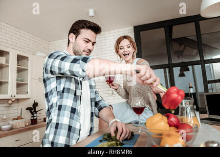 Bel homme aux cheveux noirs dans une chemise à carreaux s'amusant avec des légumes Banque D'Images