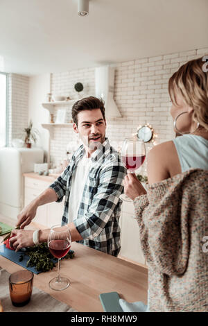 Bel homme aux cheveux noirs dans une chemise à carreaux s'amusant avec des légumes Banque D'Images