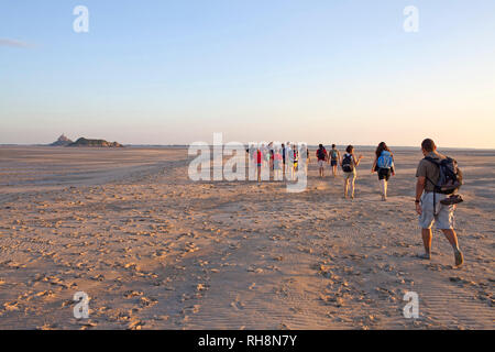 Traversée de la baie du Mont-Saint-Michel à pied (Normandie, nord-ouest de la France). Groupe de randonneurs à pied vers la petite île de Tombel de marée Banque D'Images