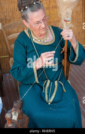 Vieille Femme en tenue médiévale traditionnelle démonstration de filage de la laine. Banque D'Images