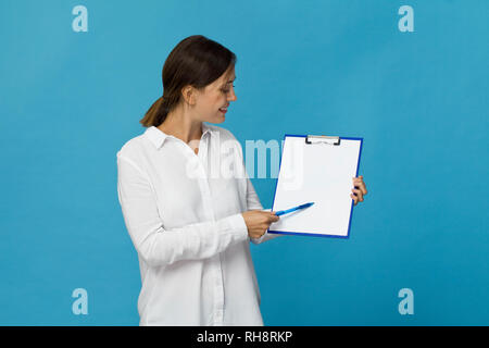 Happy brunette woman in white shirt élégant showing blank presse-papiers, isolated on white Banque D'Images