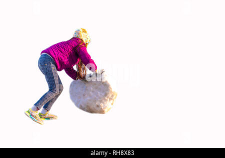 Fille non identifiée roule un gros et lourd pour construire un bonhomme de neige blanc sur fond isolé Banque D'Images