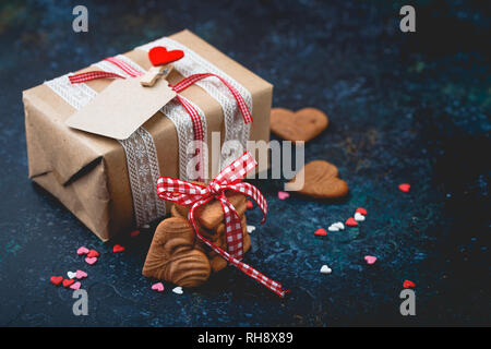 Boîte-cadeau avec arc et la pile de cookies en forme de coeur et dans le bol en bois. Cadeau romantique. Banque D'Images